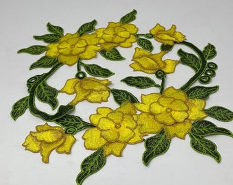 May include: Embroidered floral applique featuring bright yellow flowers and green leaves. The design includes several open blooms and detailed foliage, perfect for embellishing clothing or crafts. The applique is approximately 8 inches wide.