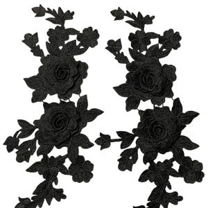 May include: Two black floral lace appliques. Each applique features a large rose surrounded by leaves and smaller flowers. The appliques are intricately detailed and suitable for embellishing garments or crafts.
