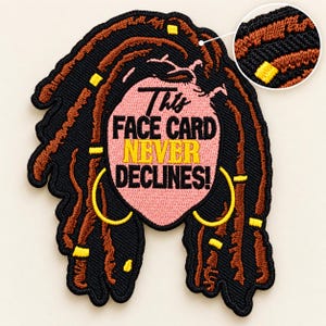 Könnte beinhalten: Ein bestickter Aufnäher mit einer rosa ovalen Gesichtsform und dem schwarz-gelben Text "This FACE CARD NEVER DECLINES!", umgeben von dunkelbraunen Dreadlocks mit gelben Akzenten und großen gelben Creolen auf einem schwarzen Hintergrund.