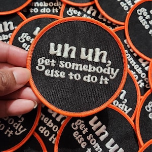 Puede incluir: Un parche redondo negro y naranja con texto bordado en blanco que dice "uh uh, get somebody else to do it".