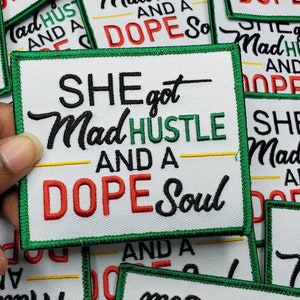 May include: A close-up of several green, yellow, and red embroidered patches with the text "She got Mad Hustle and a Dope Soul".