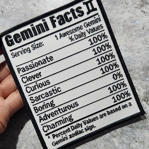 Puede incluir: Un parche blanco con texto negro que dice "Gemini Facts II" y enumera los rasgos del signo zodiacal Géminis con un valor porcentual para cada uno. Los rasgos enumerados son: Apasionado, Inteligente, Curioso, Sarcástico, Aburrido, Aventurero y Encantador. El texto en la parte inferior dice "*Los valores diarios porcentuales se basan en un signo zodiacal Géminis."