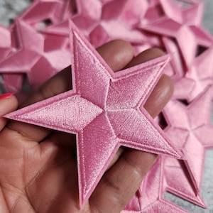 May include: A pile of pink velvet star-shaped patches. The patches are about 2 inches in diameter and have a raised, textured surface.