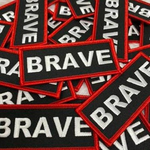 May include: A pile of black and red iron-on patches with the word "BRAVE" in white lettering.