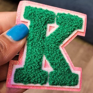 1 parche de chenilla con la letra "K" verde y purpurina rosa, con fieltro blanco, tamaño 2.75", con letras universitarias y reverso termoadhesivo, letras pequeñas de chenilla.