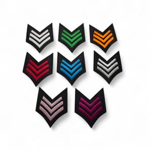 May include: Nine embroidered chevron patches in various colors, including white, green, orange, red, blue, silver, pink, and purple. Each patch features a black border and a chevron design, suitable for uniforms or crafts.