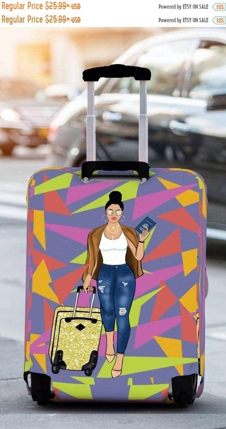 Puede incluir: Una funda de maleta morada con un patr&oacute;n geom&eacute;trico de tri&aacute;ngulos rosas, naranjas y amarillos. Una ilustraci&oacute;n de dibujos animados de una mujer con un pasaporte en la mano est&aacute; en la funda. La funda de maleta est&aacute; en una maleta con ruedas negras.