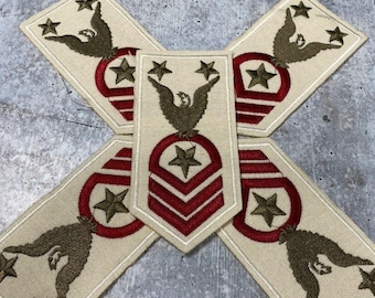 May include: Four beige fabric patches with embroidered red, white, and gold stars, eagles, and stripes. The patches are arranged in a cross shape.