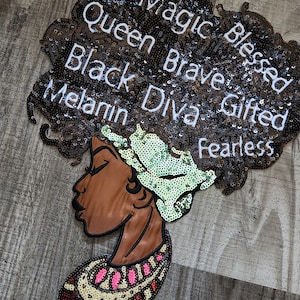 May include: A black and brown sequined patch with a profile of a woman's face. The woman's hair is styled in an afro and has the words "Magic Blessed Queen Brave Gifted Black Diva Melanin Fearless" written on it.