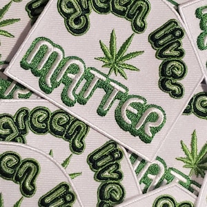 Puede incluir: Primer plano de varios parches bordados en verde y blanco con las palabras "green lives matter" y un diseño de hoja de marihuana.