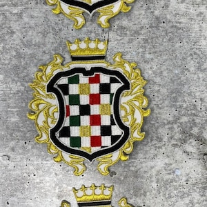 May include: Three gold embroidered patches with a checkered pattern in black, white, red, and green. Each patch features a gold crown and ornate gold scrollwork.