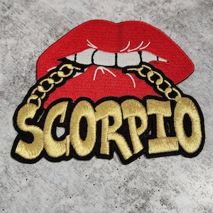 May include: Red lips with gold chain and the word "SCORPIO" in gold letters on a black background.