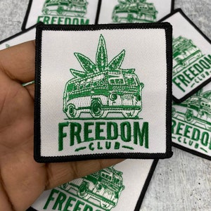 May include: White square patch with a green design featuring a van with a cannabis leaf on top and the words "FREEDOM CLUB" in green. The patch has a black border. Several patches are visible.