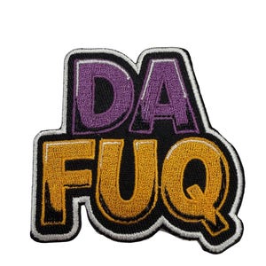 May include: An embroidered patch featuring the text DA FUQ in bold, block-style lettering. The word DA is stitched in purple, while the word FUQ is in gold. The entire design is outlined in thick black and white thread borders on a black background.