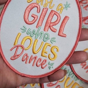 Könnte beinhalten: Gestickter Aufnäher mit dem Text "Just a GIRL who LOVES Dance" in Koralle, Gelb und Grün. Der Aufnäher hat einen weißen Hintergrund und einen korallenfarbenen Rand. Mehrere Aufnäher sind sichtbar.