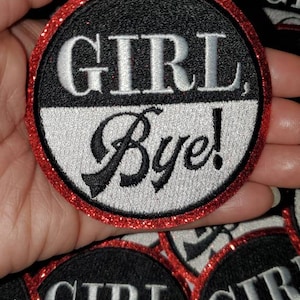 May include: A set of round, black and white embroidered patches with red glitter trim. The patches say "Girl Bye!" in white and black lettering.