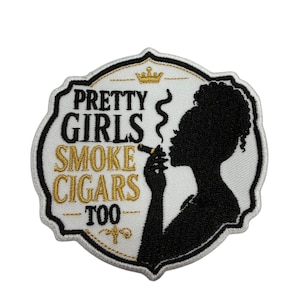 May include: An embroidered patch with a white background and black border. It features a black silhouette of a person with a cigar and smoke, a gold crown, and the text PRETTY GIRLS SMOKE CIGARS TOO in black and gold thread on a white field.