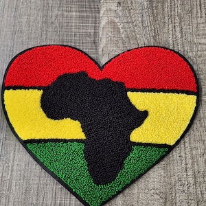 May include: A red, yellow, and green heart-shaped patch with a black outline. The center of the heart features a black silhouette of the continent of Africa.