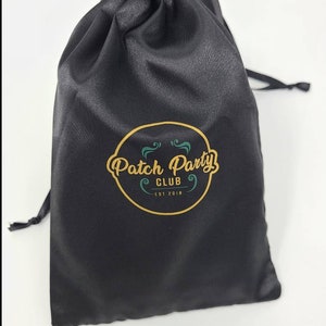 May include: Black satin drawstring bag with a gold and green logo that says "Patch Party Club Est 2018"