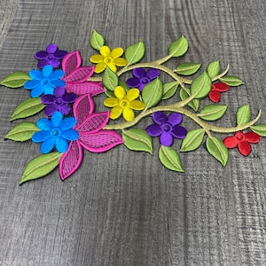 Puede incluir: Parche de aplique floral bordado con flores rosas, azules, amarillas y moradas sobre tallos verdes. El parche es perfecto para añadir un toque de encanto floral a la ropa, los bolsos o los proyectos de decoración del hogar.