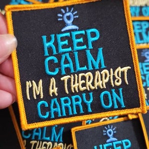 Pode incluir: Um monte de patches bordados pretos e amarelos para passar a ferro com o texto "Keep Calm I'm a Therapist Carry On".