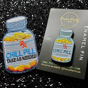 May include: An embroidered patch and enamel pin featuring a blue pill bottle design. The patch and pin both read "CHILL PILL TAKE AS NEEDED" with yellow pill graphics. The pin is on a black card with "ENAMEL PIN" text.