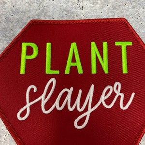 May include: Red octagon-shaped patch with the text "PLANT slayer" in green and white embroidery.