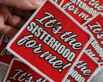 May include: Red and white embroidered patches with the text "It's the SISTERHOOD for me!". The patches have a white border and are square with rounded corners. Several patches are visible.