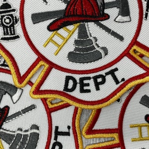 Op de afbeelding: Close-up van drie geborduurde patches met een brandweerthema. De patches zijn wit met rode en gouden randen. De middelste patch heeft een brandkraan, een bijl en een ladder. De tekst "DEPT." is in het zwart geborduurd aan de onderkant van de patch.