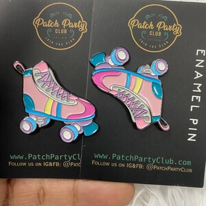 K&ouml;nnte beinhalten: Zwei Emaille-Pins mit einem Paar rosa Rollschuhen mit blauen, gelben und violetten Akzenten. Die Pins befinden sich auf einem schwarzen Hintergrund mit dem Text "Patch Party Club" und Website-Informationen.