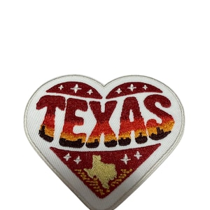 Può includere: Una toppa ricamata a forma di cuore con bordo bianco. La parola TEXAS è ricamata in una sfumatura di rosso, arancione e giallo. Sotto il testo, una sagoma dorata dello stato del Texas è centrata su uno sfondo rosso con stelle bianche.