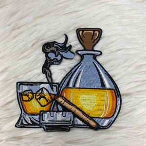 Puede incluir: Un parche bordado que presenta un vaso de whisky con hielo, un cigarro encendido y una botella de licor. El parche está en tonos de azul, amarillo y marrón.