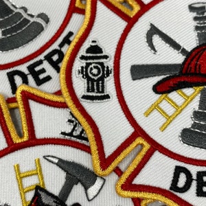 Op de afbeelding: Close-up van een set geborduurde patches met een brandweerthema. De patches zijn wit met rode en gouden randen. Ze bevatten een brandkraan, een ladder, een bijl en een brandweerhelm.