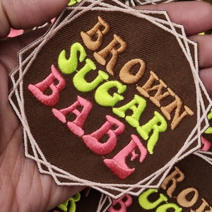 May include: Brown fabric patch with the text "BROWN SUGAR BABE" in pink, yellow, and orange embroidery.