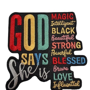 Puede incluir: Un parche bordado negro con el texto "GOD SAYS She is" en letras grandes rojas, amarillas y verde azulado. A la derecha, palabras más pequeñas están apiladas: "MAGIC", "Intelligent", "BLACK", "Beautiful", "STRONG", "Powerful", "BLESSED", "Brave", "LOVE", "Influential".