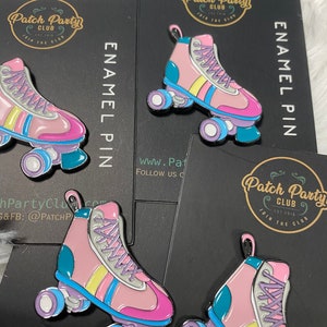 K&ouml;nnte beinhalten: Eine rosa und blaue Emaille-Anstecknadel mit einem Paar Rollschuhen mit gelben und wei&szlig;en Streifen. Die Anstecknadel hat ein wei&szlig;es und graues Schn&uuml;rdesign und eine t&uuml;rkisfarbene Basis. Der Text "Patch Party Club" ist auf der Anstecknadel sichtbar.