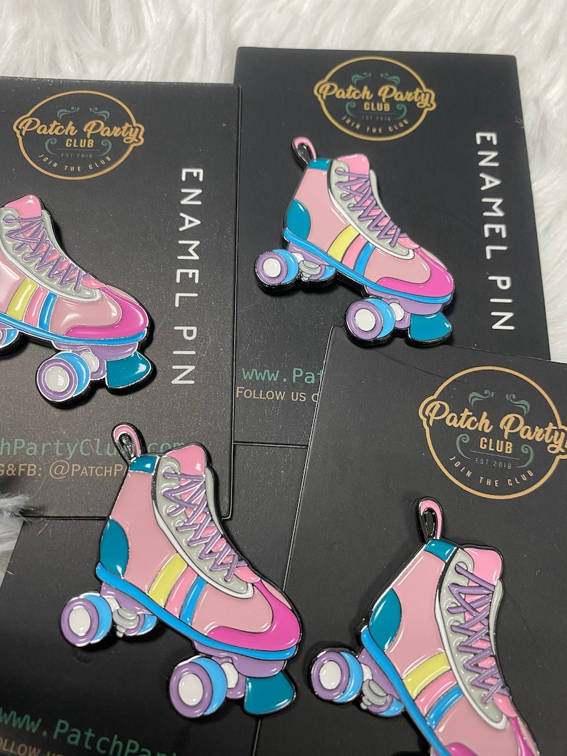 K&ouml;nnte beinhalten: Eine rosa und blaue Emaille-Anstecknadel mit einem Paar Rollschuhen mit gelben und wei&szlig;en Streifen. Die Anstecknadel hat ein wei&szlig;es und graues Schn&uuml;rdesign und eine t&uuml;rkisfarbene Basis. Der Text "Patch Party Club" ist auf der Anstecknadel sichtbar.