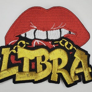 May include: Embroidered patch featuring a red mouth with white teeth and the word "LIBRA" in gold lettering with a black outline. The patch has a chain design.