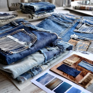 Może przedstawiać: Zbliżenie dżinsów z przetarciami, łatami i postrzępionymi krawędziami. Widoczne są różne odcienie niebieskiego denimu, a także próbki tkanin i paleta kolorów, co sugeruje skupienie się na projektowaniu tekstyliów i modzie.