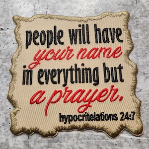 May include: Embroidered patch with the text "people will have your name in everything but a prayer." The text is in black and red thread on a tan background with a decorative border. The text "hypocritelations 24:7" is also included.