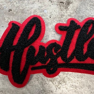 May include: A red felt patch with the word "Hustle" embroidered in black yarn.