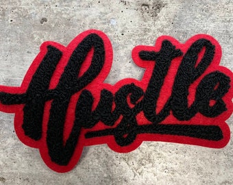 May include: A red felt patch with the word "Hustle" embroidered in black yarn.
