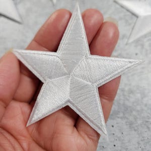 Op de afbeelding: Een witte, 3D geborduurde sterpatch. De ster is een vijfpuntige ster met een verhoogd, getextureerd oppervlak.