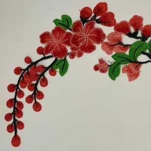 May include: Embroidered floral applique featuring red flowers and berries with green leaves and black stems. The design is a corner accent, suitable for embellishing clothing or crafts. The embroidery is detailed and vibrant.