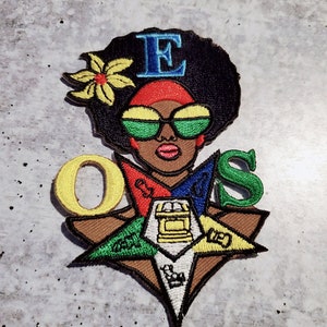 May include: Embroidered patch featuring a woman with an afro, sunglasses, and a red headband. The patch also includes a five-pointed star with the letters "O.E.S." and a gold square and compass in the center.