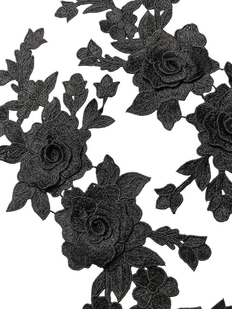 May include: Close-up of black floral lace appliques. The appliques feature detailed embroidered roses, buds, and leaves. The lace is intricately designed with a textured appearance, ideal for embellishing garments or crafts.