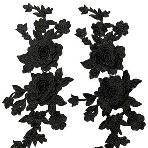 May include: Two black floral lace appliques. Each applique features a large rose surrounded by leaves and smaller flowers. The appliques are detailed and have a three-dimensional appearance, suitable for embellishing garments or crafts.