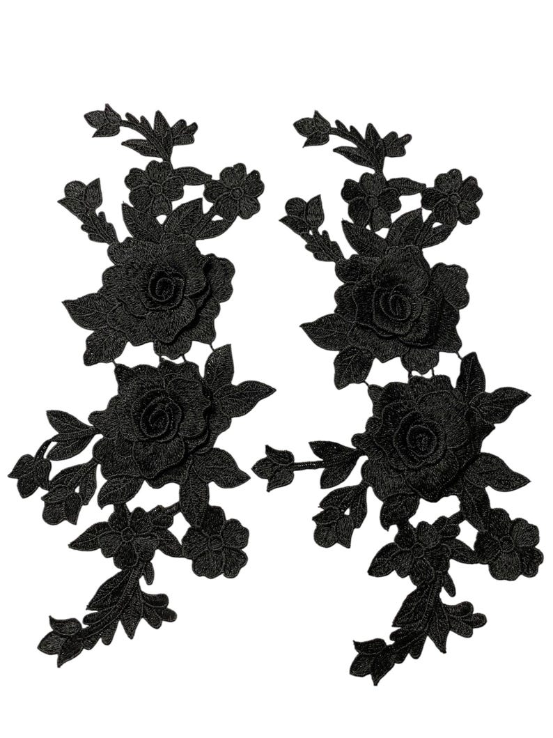 May include: Two black floral lace appliques. Each applique features a large rose surrounded by leaves and smaller flowers. The appliques are detailed and have a three-dimensional appearance, suitable for embellishing garments or crafts.