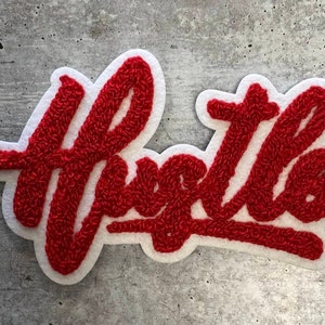 May include: White felt patch with the word "Hustle" embroidered in red yarn.