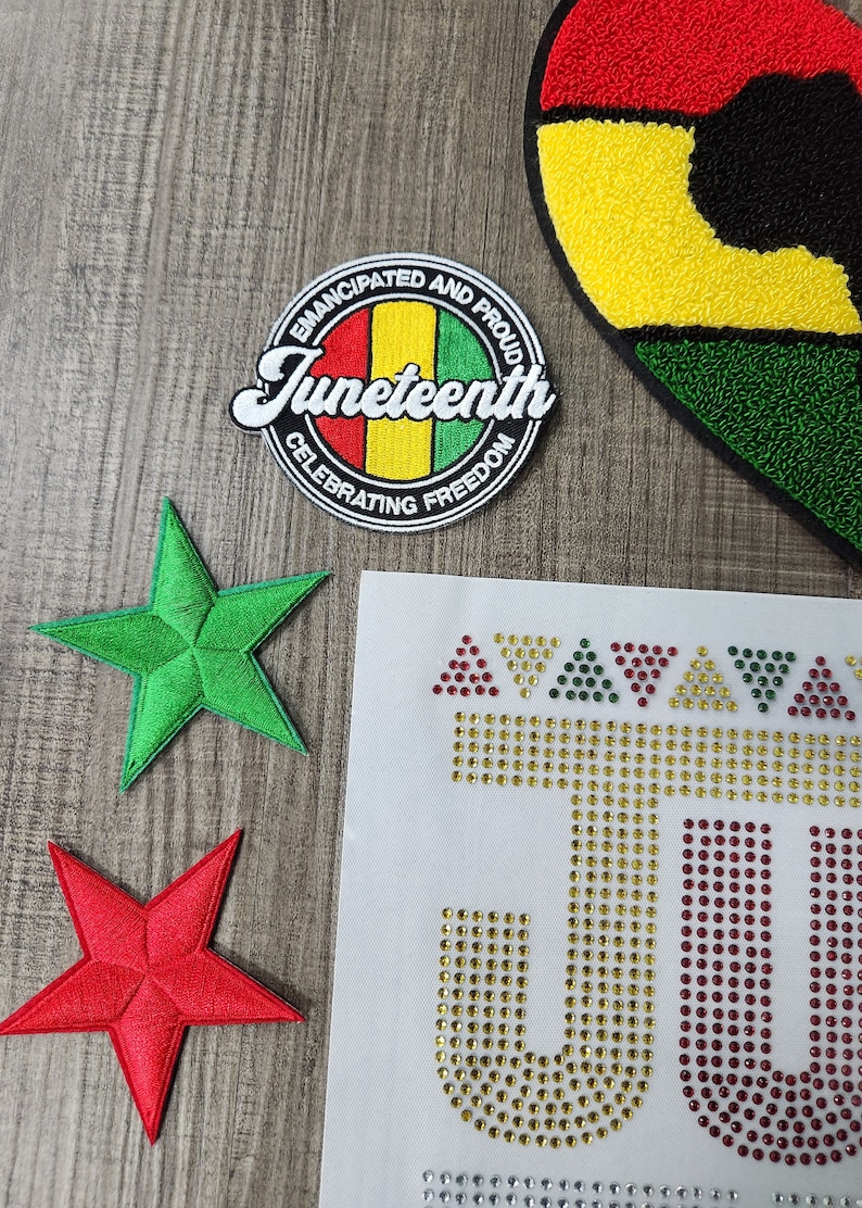 May include: A set of iron-on patches featuring a red, yellow, and green heart, a green five-pointed star, a red five-pointed star, and a round patch with the text "Emancipated and Proud Juneteenth Celebrating Freedom".
